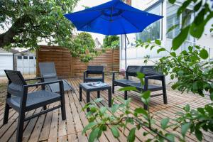 a patio with four chairs and a blue umbrella at Le Grand Coquet in Besançon