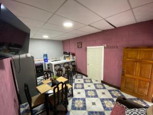 a kitchen with tables and chairs and pink walls at Casa Cahuí in El Remate