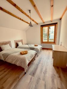Habitación con 2 camas, suelo de madera y ventana. en Chez Pierre et Fabienne, en Le Locle