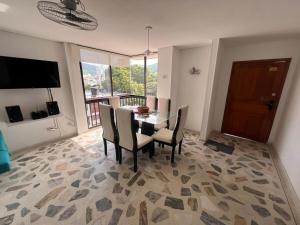 a dining room with a table and chairs and a television at Apartamento cerca a la playa en el rodadero in La Tigrera +9 photos