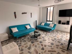 a living room with two blue couches and a flat screen tv at Apartamento cerca a la playa en el rodadero in La Tigrera