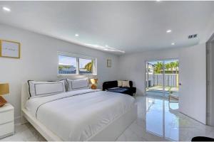 a white bedroom with a large bed and a chair at Magical Miami Retreat with Heated Pool, Mini Golf, and Basketball Court L19 in Miami +49 photos