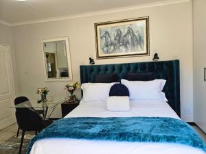 a bedroom with a large bed with a blue blanket at The Little Haven in Midrand