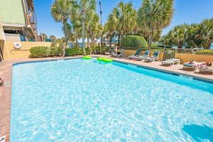einen großen Pool mit Palmen und Stühlen in der Unterkunft Amazing View Ocean Front Studio Nicely Decorated in Myrtle Beach