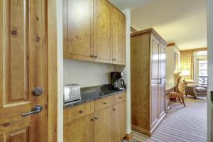 une cuisine avec des armoires en bois et un réfrigérateur dans l'établissement StoweBound at The Lodge at Spruce Peak, à Stowe Mountain 19 autres photos