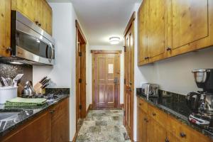 une cuisine avec des placards en bois et des comptoirs noirs dans l'établissement StoweBound at The Lodge at Spruce Peak, à Stowe Mountain