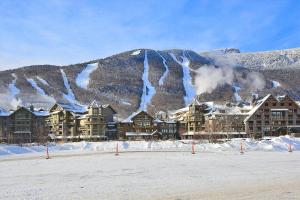 un complexe dans la neige avec une montagne en arrière-plan dans l'établissement StoweBound at The Lodge at Spruce Peak, à Stowe Mountain