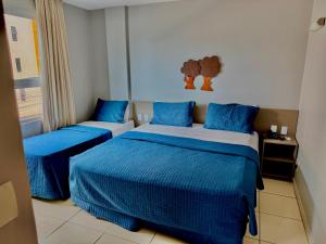 a bedroom with two beds with blue comforters at Hotel Green Sunset 407 in João Pessoa