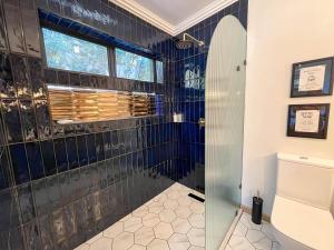 a bathroom with a shower with blue tiles at Treetop Guesthouse in Gqeberha +23 photos