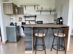 une cuisine avec deux tabourets de bar à un comptoir dans l'établissement Xie House, à Ubalá