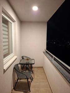 two chairs and a table in a room with a large window at Stan na dan Ramonda in Donje Mladice