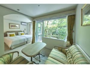 a bedroom with a bed and a table and a couch at Auberge de Primavera - Vacation STAY 40836v in Shin-karuisawa