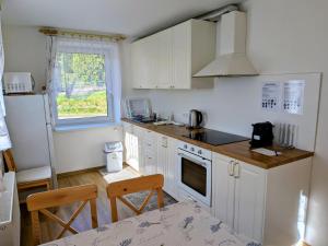 a kitchen with white cabinets and a table and a window at Apartmány U Zvoničky in Prachov