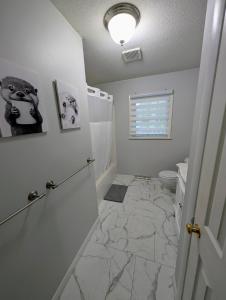 a bathroom with a marble floor and a toilet at Summit & Shore House, Whole House in Colchester