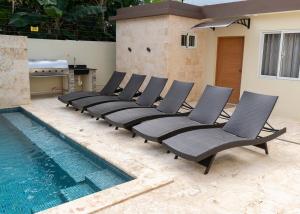 a row of chairs next to a swimming pool at La Isla Royal - Pool Side Suite in Miches