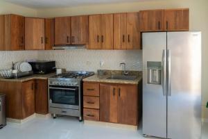 a kitchen with wooden cabinets and a stainless steel refrigerator at La Isla Royal - Pool Side Suite in Miches