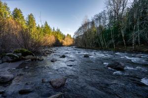 einen Fluss mit Felsen und Bäumen im Hintergrund in der Unterkunft Stay Portland - Alpine Retreat Hot Tub, Fire Pit & Game Room in Rhododendron