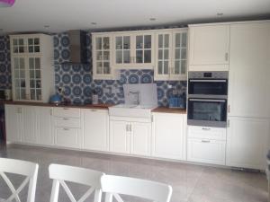 una cocina blanca con armarios blancos y sillas blancas en Brownes Town House en Dungarvan