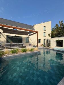 a swimming pool in front of a building at Charmante maison avec piscine in Turquant