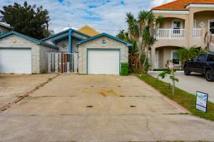 a house with two garage doors in a driveway at BBQ ok Ground Floor Duplex 1-2 block to Beach in South Padre Island