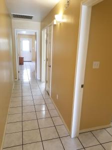 a hallway with yellow walls and a tile floor at BBQ ok Ground Floor Duplex 1-2 block to Beach in South Padre Island