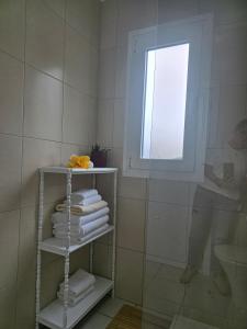 a bathroom with a shelf with towels and a window at Casa da Cruz in Machico