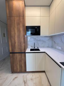 a kitchen with white cabinets and a sink at Apartment Uman in Umanʼ