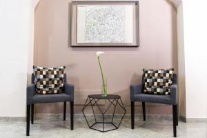 two chairs and a vase with a flower on a table at Hotel Florence Milano in Milan