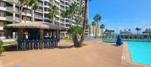 a resort with a pool and chairs and a building at Resort like super heated pool & direct beach front in South Padre Island