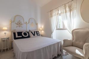 a bedroom with a white bed and a chair at Casa Lilliosa in San Pasquale