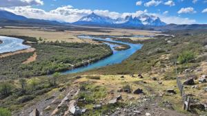 a river in a valley with mountains in the background at Camping Río Serrano - Caja Los Andes in Torres del Paine