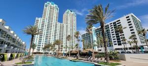 a resort pool with palm trees and buildings at Luxury 17th Floor Beachfront Stunning Views in South Padre Island
