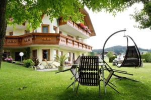 a couple of chairs sitting in the grass in front of a house at Haus zur Sonne in Sankt Urban