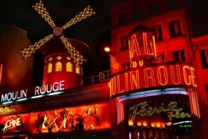 a building with neon signs on it at night at Basilica of the Sacred Heart - Heart of Montmartre in Paris