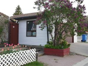 a white fence in front of a house with a tree at Calgary Star Cozy Home in Calgary