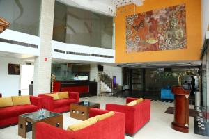 a lobby with red chairs and tables in a building at Hotel Rajshree & Spa in Chandīgarh +11 photos