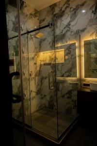 a glass shower in a bathroom with a stone wall at Awka Luxury One Bed in Awka +9 photos