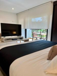 a bedroom with a large bed with a flat screen tv at Suites - Llanogrande in Rionegro