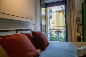 una cama con almohadas rojas en una habitación con balcón en Navigli - LeoBrothers - Alzaia Naviglio Pavese 8, en Milán