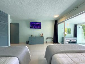 Un dormitorio con dos camas y un televisor en la pared. en Gran Suite Cancun - Beach Condo, en Cancún