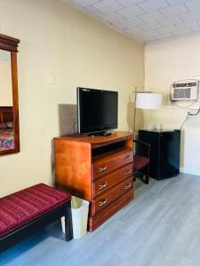 ein Wohnzimmer mit einem Fernseher auf einer Kommode mit einer Bank in der Unterkunft Budget Motel in Manning