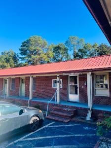 ein Auto, das vor einem Backsteingebäude mit rotem Dach geparkt ist in der Unterkunft Budget Motel in Manning