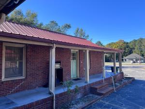 ein rotes Backsteinhaus mit einer Veranda und einer Tür in der Unterkunft Budget Motel in Manning + 9 Fotos