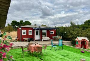 a red tiny house with a table and chairs at Casita Campo 15 minutos Aeropuerto Ifema y Plaza Castilla in Madrid