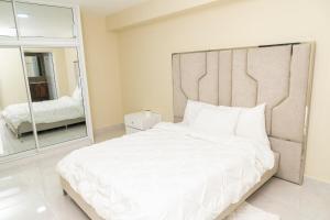 una camera da letto con un grande letto bianco e uno specchio di La Isla Royal - Luminancia Eterna a Miches