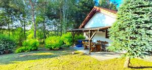 a small house with a wooden deck in a yard at Dom nad Stawem Pokoje Gościnne 