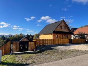 a house with a wooden fence in front of it at Osada na Skale Domek z kominkiem in Istebna