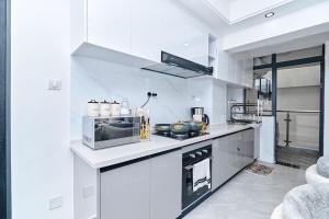 a white kitchen with a microwave and a stove at Luxury Lush Home in Nairobi