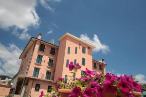 サン・ジョヴァンニ・ロトンドにあるHotel Leon - Ristorante Al Cavallino Rossoの紫色の花々が目の前に咲くピンクの建物