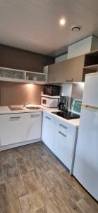 a kitchen with white cabinets and a white refrigerator at Chalet JACUZZI/spa privatif PERCE NEIGE in Plombières-les-Bains +15 photos